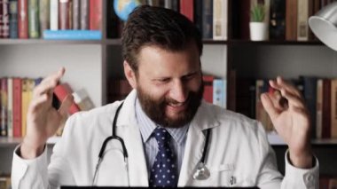 Neşeli doktor alkol içer. İş yerinde harika bir ruh hali içinde olan erkek doktor kahverengi alkolik konyak ya da viskiyi bardağa ve içeceğe çevirir.