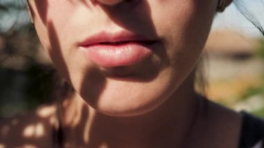 Kız böğürtlen yiyor. Genç bir kadın güneşli bir günde ağzına ahududu koyar. Yakın plan.