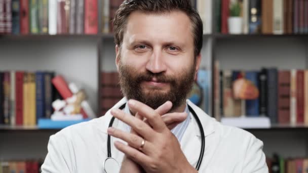 医者は拍手する。オフィスでの白衣と聴診器で優しい笑顔男性医師は、カメラを見て、何かで喜んで彼の手で拍手 — ストック動画