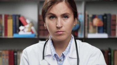 Doktor dur diyor. Beyaz önlüklü ve steteskop giymiş heyecanlı kadın doktor kameraya bakıyor elini kaldırıyor ve avuç içiyle DUR işaretini gösteriyor.