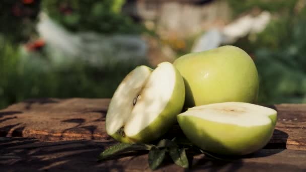 Gröna äpplen ligger på träbord ute på solig dag i naturen. Närbild — Stockvideo