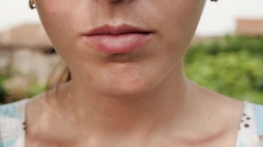 Kadın şeftali suyu içiyor. Kadın eli, şeftali suyuyla birlikte bardağı getirir ve doğanın güneşli bir gününde içer. Yakın plan.