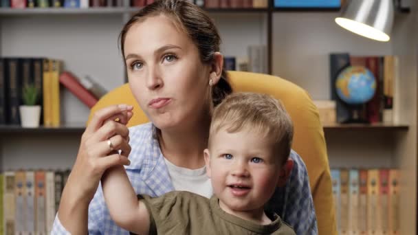 Máma a malý dítě koukají na televizi a jedí popcorn, dítě krmí mámu popcornem. Detailní záběr — Stock video