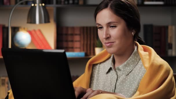 Egy nő dolgozik a laptopon. Jó hangulatú lány jó hangulatban egyedül este vagy éjszaka a szobában csomagolt takaró használ laptop, szörfözés Internet vagy ő csevegés — Stock videók