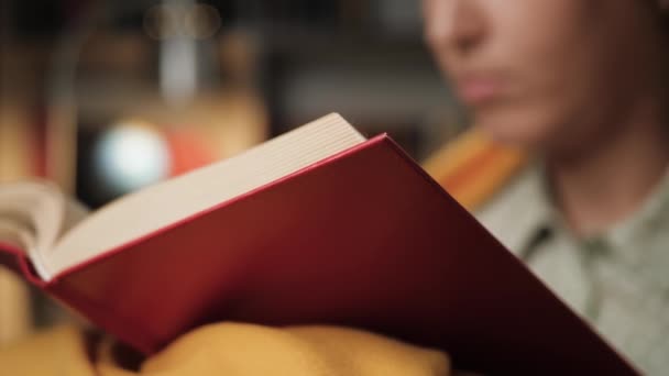 Quella donna sta leggendo un libro. La ragazza legge il libro la sera, gira pagina. Primo piano — Video Stock