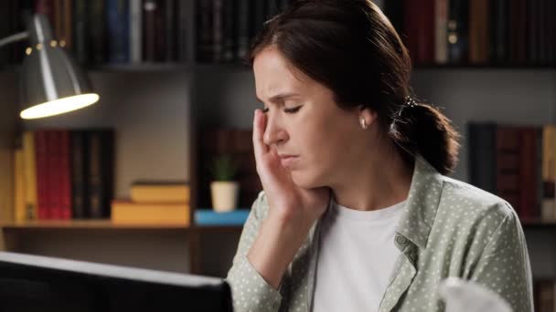 Tomando pastillas para el dolor. Mujer cansada en el lugar de trabajo por la noche trabaja en el ordenador portátil, se toca la cabeza y saca la botella y toma una tableta con agua. Dolor de cabeza, concepto de presión arterial alta o baja — Vídeos de Stock