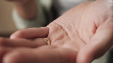 İki beyaz hap bir kadın avucuna bir kutu haptan düşüyor. Yakın plan.