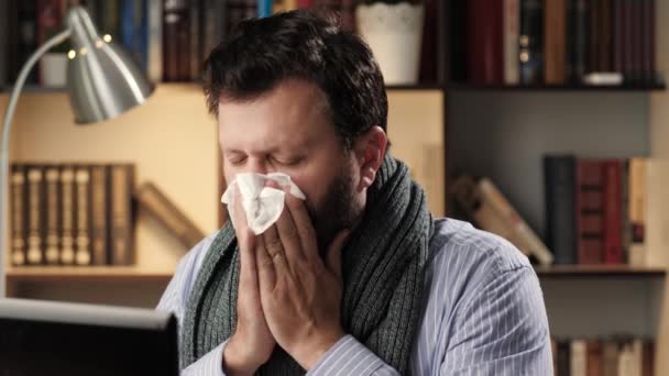 Насморк, заторы в носу. Человек с простудой на рабочем месте в офисе или квартире работает на ноутбуке, высморкается в салфетку и использует назальный спрей. Концепция лечения холодного гриппа — стоковое видео