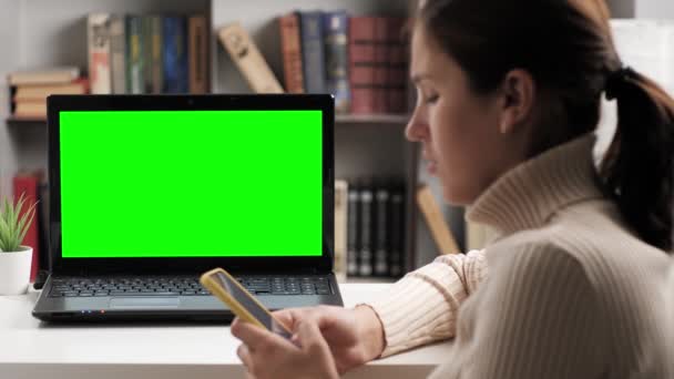 Kvinnan sitter vid bordet och tittar på grön skärm laptop, skriver hon in på skärmen tangentbord och talar på internet online video anslutning. Chroma nyckel dator skärm kvinna talar på videosamtal — Stockvideo