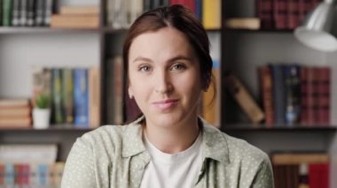 Bir kadın parmak işareti yapıyor. Ofiste ya da dairede gülümseyen mutlu bir kadın kameraya bakar ve onu işaret eder.