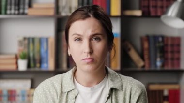 Bir kadın parmak işareti yapıyor. Ofiste ya da dairede somurtan kızgın kadın kameraya bakar ve parmaklarıyla işaret eder ve onu davet eder.