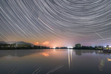Kuyrukluyıldız Neowise ile yıldız izleri ve arka planda çarşaf olan bir göktaşı gölde yansıyor.