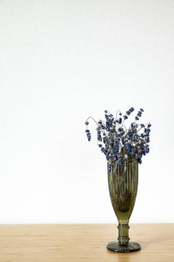 Ahşap masadaki vazoda kurutulmuş lavanta çiçekleri.