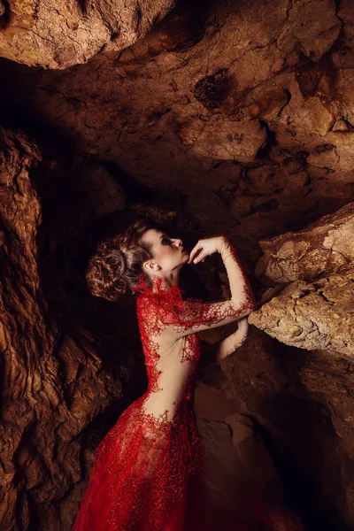 ダイナミックなファッションショット 赤いドレスのセクシーな女性暗い洞窟でゴシックの妖精の撮影 赤の洞窟 クリミア — ストック写真