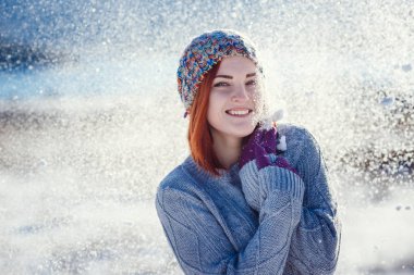 Winter portrait of young beautiful brunette woman wearing knitted snood covered in snow. Snowing winter beauty fashion concept. clipart