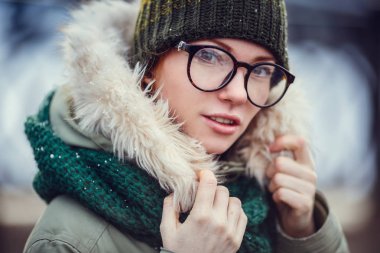 Soğuk bir kış akşamında gün batımında sokakta yürürken ceketli mutlu kız.