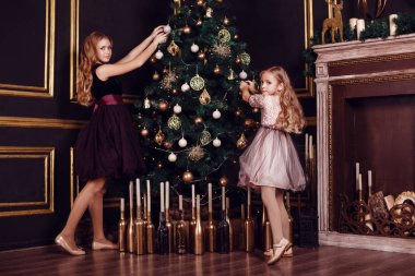 Mumlar ve hediyelerle köknar ağacı ve şömine önünde rahibeler. Yeni yıl arifesi. Noel arifesi. Köknar ağacında sıcak bir tatil Işıklar ve altın dekor ile.