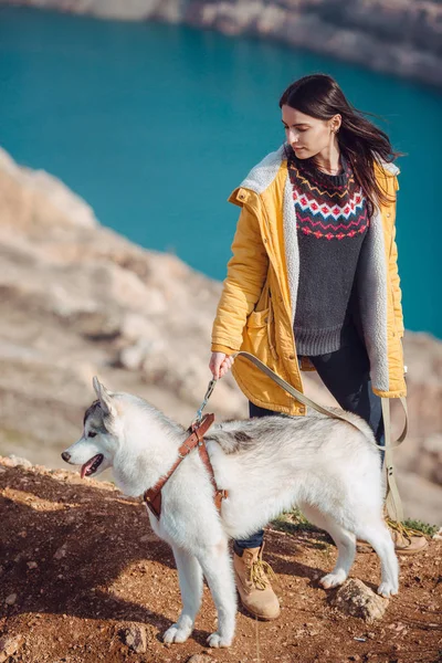 Jong vrouwtje zittend met siberische husky hond in bergen — Stockfoto