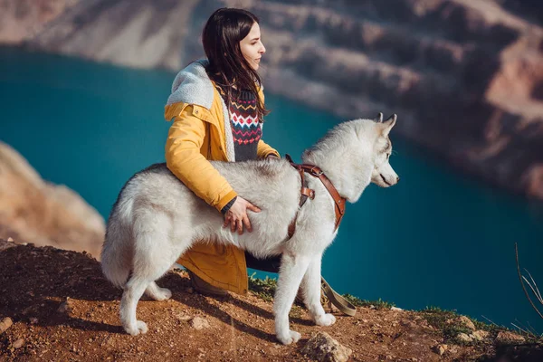 Jovem fêmea sentada com cão husky siberiano nas montanhas — Fotografia de Stock