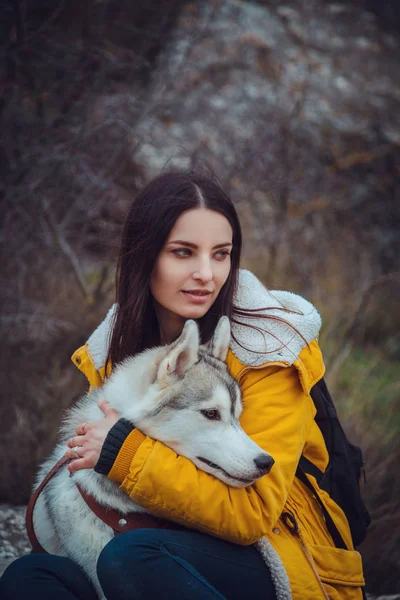 Jong vrouwtje zittend met siberische husky hond in bergen — Stockfoto