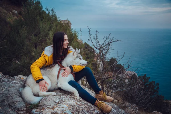 Jong vrouwtje zittend met siberische husky hond in bergen — Stockfoto