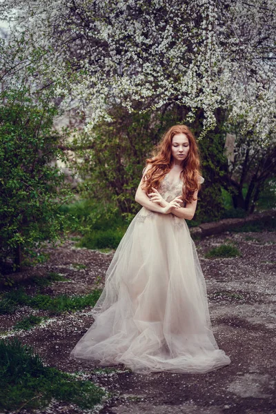 赤い髪と開花の春の庭の香りを楽しむ美しい幸せな若い女 — ストック写真