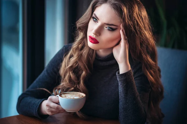 Kávé cappuccino-hab közelében ablak egy kávézóban, élvezheti a gyönyörű fiatal nő — Stock Fotó