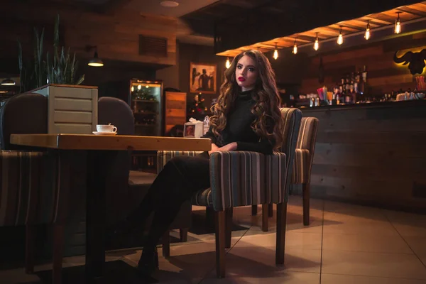 Hermosa joven mujer disfrutando de café capuchino con espuma cerca de la ventana en un café —  Fotos de Stock