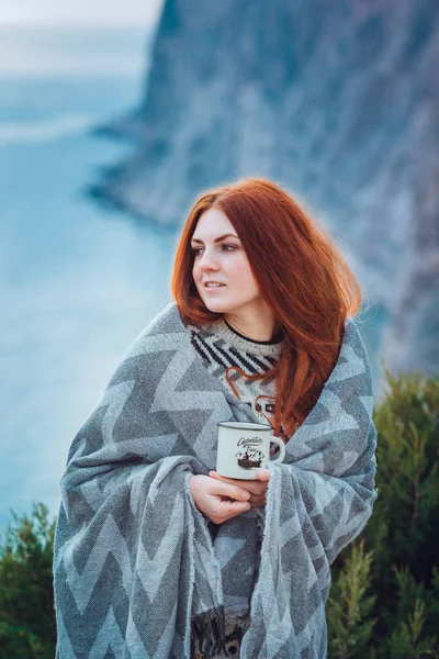beautiful redhead young woman with freckles enjoying the beauty of nature walking by the sea