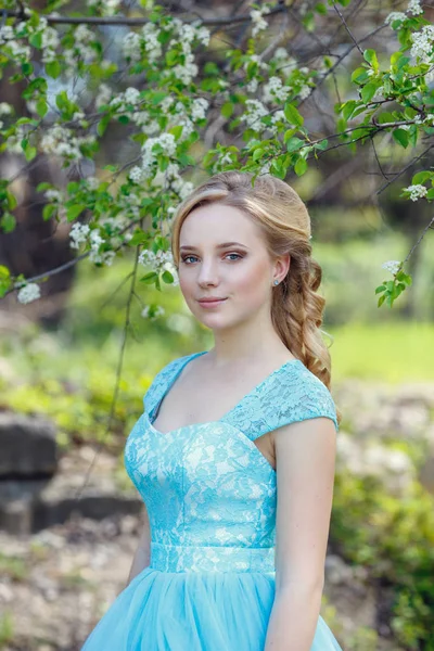 Bella bionda giovane donna che indossa vestiti alla moda passeggiando nel parco primaverile . — Foto Stock