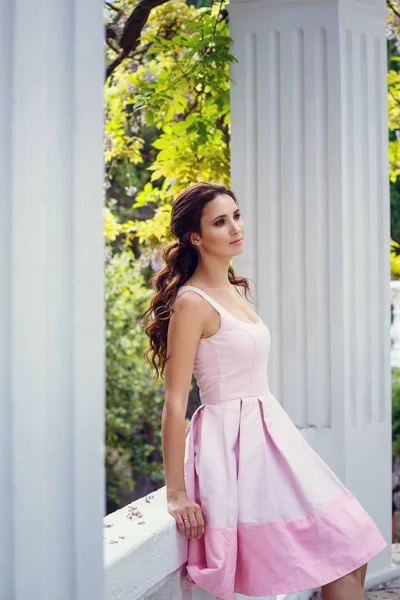 Fashion outdoor photo of gorgeous woman with dark hair in elegant pink dress posing at summer park — Stock Photo, Image