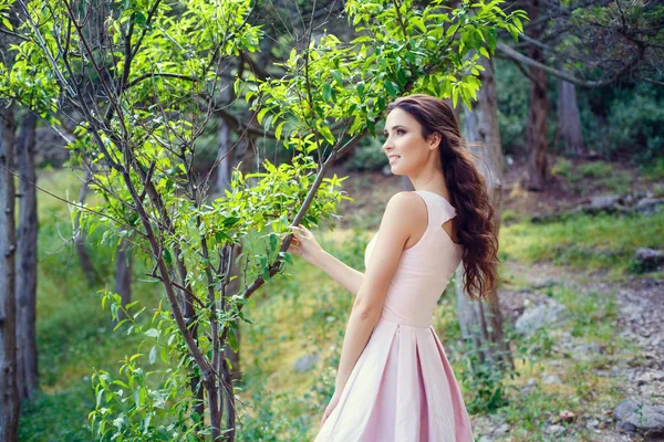 Foto al aire libre de moda de mujer hermosa con cabello oscuro en vestido rosa elegante posando en el parque de verano — Foto de Stock