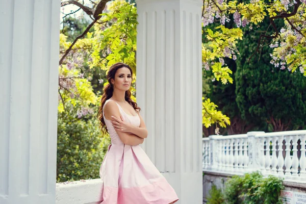 Модна зовнішня фотографія чудової жінки з темним волоссям в елегантній рожевій сукні позує в літньому парку — стокове фото