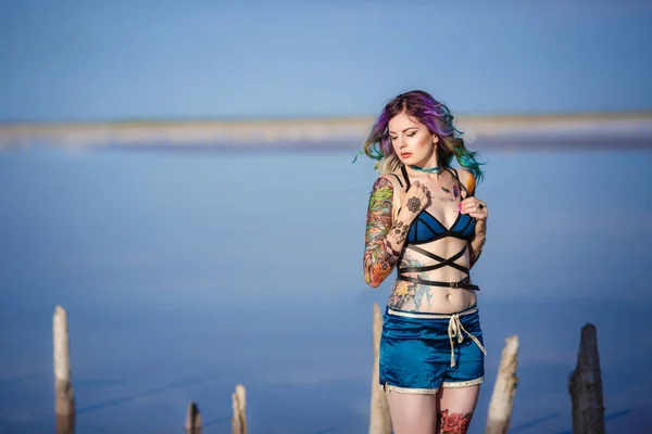 Sexy woman on the sand beside a lake with a pink water — Stock Photo, Image