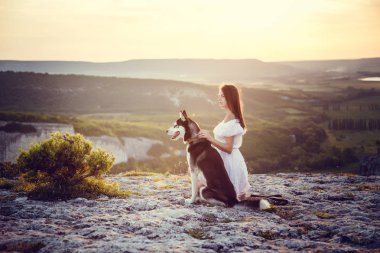 Güzel ve genç birbayan gündoğumu veya günbatımı park açık havada komik husky köpek ile oynamak