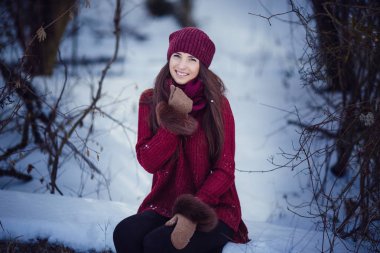 Sıcak kış giysileri ve kar kış ormanda üfleme şapka giyen bir kız.