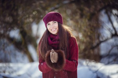 Sıcak kış giysileri ve kar kış ormanda üfleme şapka giyen bir kız.