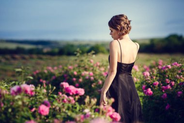 Güzel genç kadın bir çiçek gül bahçesinde