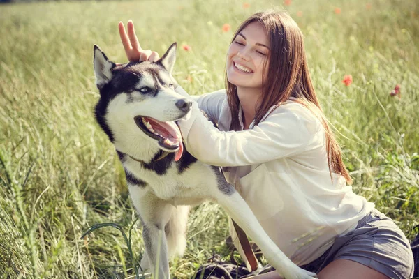 Ung vacker flicka som leker med en hund. Leker med hunden på parken. Närbild porträtt. Siberian husky. — Stockfoto