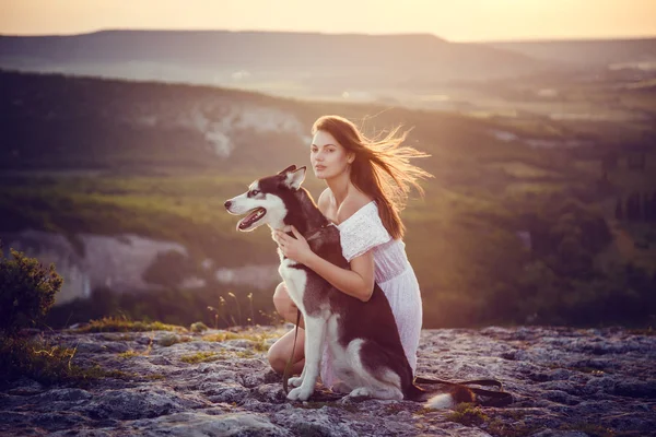 Belle jeune femme jouant avec chien husky drôle à l'extérieur dans le parc au coucher du soleil ou au lever du soleil — Photo
