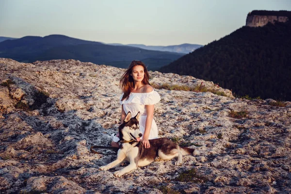 Belle jeune femme jouant avec chien husky drôle à l'extérieur dans le parc au coucher du soleil ou au lever du soleil — Photo