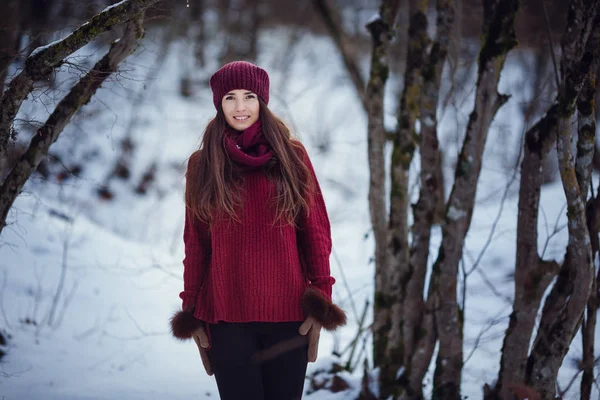 Una chica que usa ropa cálida de invierno y sombrero que sopla nieve en el bosque de invierno . —  Fotos de Stock