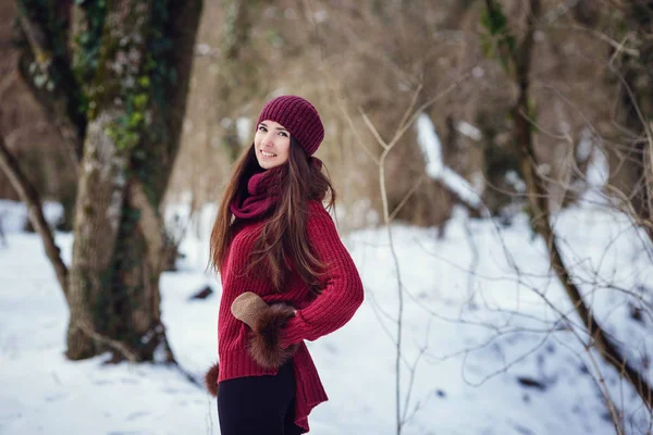 Una ragazza che indossa vestiti invernali caldi e cappello che soffia neve nella foresta invernale . — Foto Stock