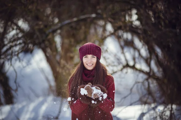 Sıcak kış giysileri ve kar kış ormanda üfleme şapka giyen bir kız. — Stok fotoğraf