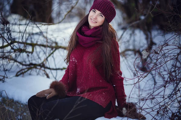 Uma menina vestindo roupas quentes de inverno e chapéu soprando neve na floresta de inverno . — Fotografia de Stock