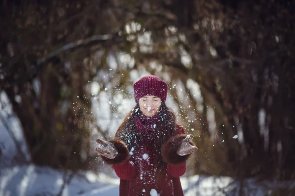 暖かい冬の服と冬の森の雪を吹き帽子を身に着けている女の子. — ストック写真