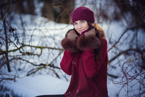 Una chica que usa ropa cálida de invierno y sombrero que sopla nieve en el bosque de invierno . —  Fotos de Stock