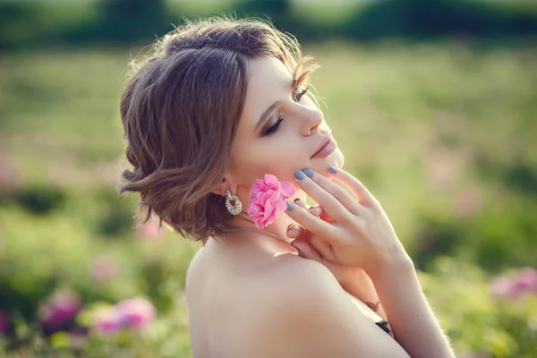 Belle jeune femme dans une roseraie fleurie — Photo