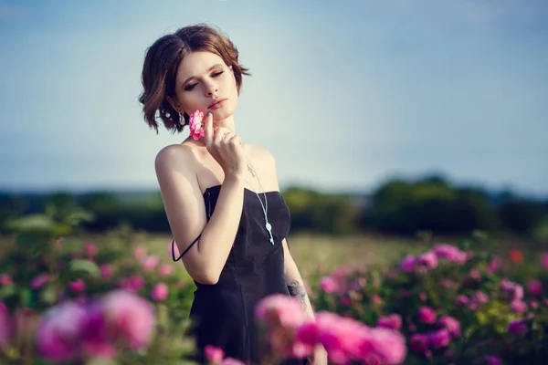 Belle jeune femme dans une roseraie fleurie — Photo