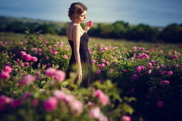 Mulher bonita em um jardim de rosas florescendo — Fotografia de Stock